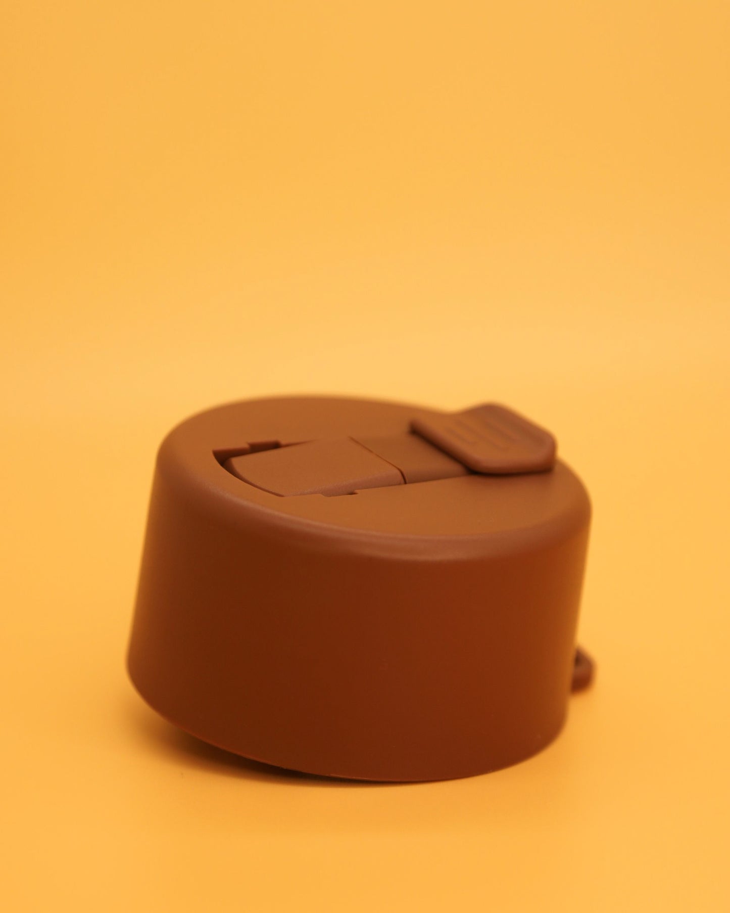 Brown circular water bottle lid on an orange background