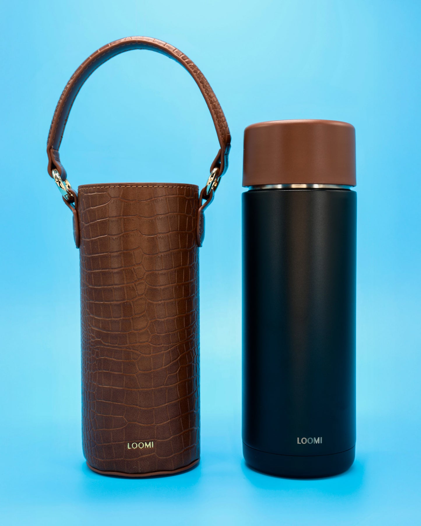 Brown textured croc textured bottle cover and black insulated water bottle with brown lid on a blue background