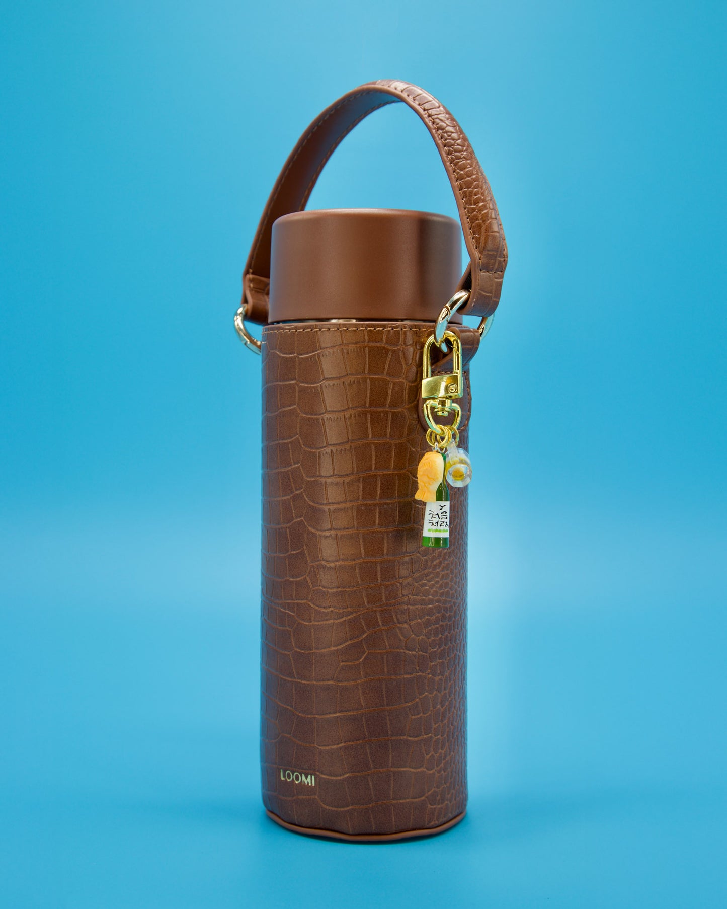 Mini Soju features a mini green soju bottle charm, a cute taiyaki fish, and a frosty beer mug clasp clipped on the side of a brown faux croc cover water bottle on blue background