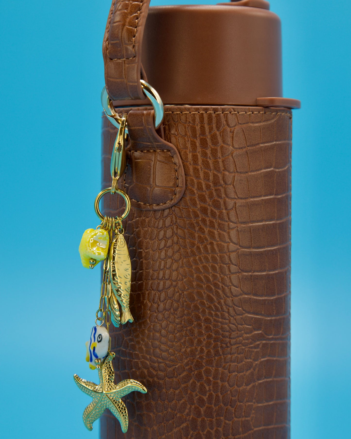 Brown textured bottle with a keychain featuring a fish and starfish charm on a blue background