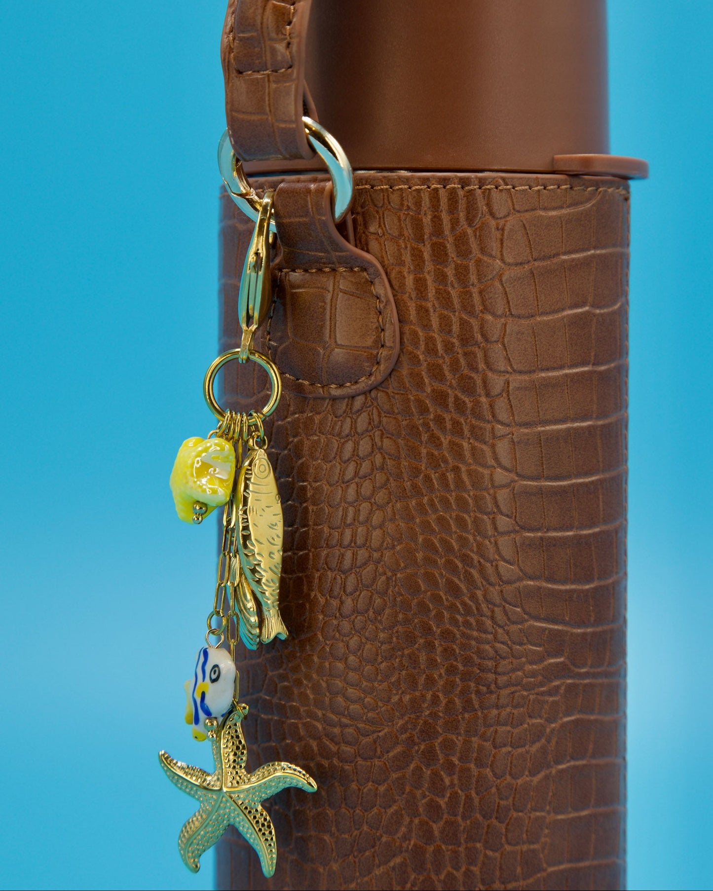 Brown textured bottle with a keychain featuring a fish and starfish charm on a blue background