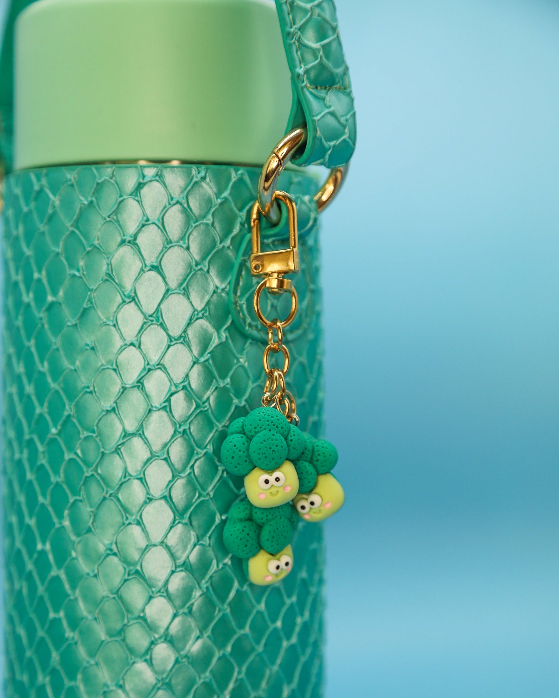 Broccoli charm hanging from mermaid-green Loomi Slip on a water bottle”