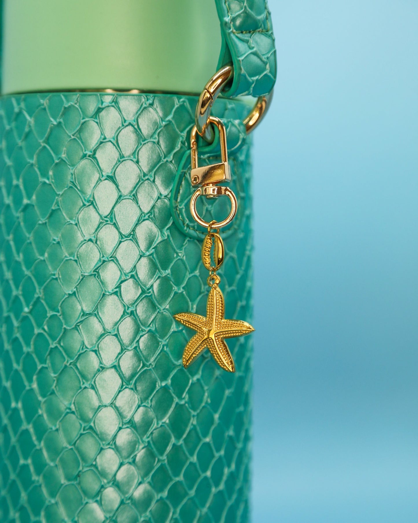 Gold starfish charm clipped to a mermaid-green Loomi Slip (water bottle cover)