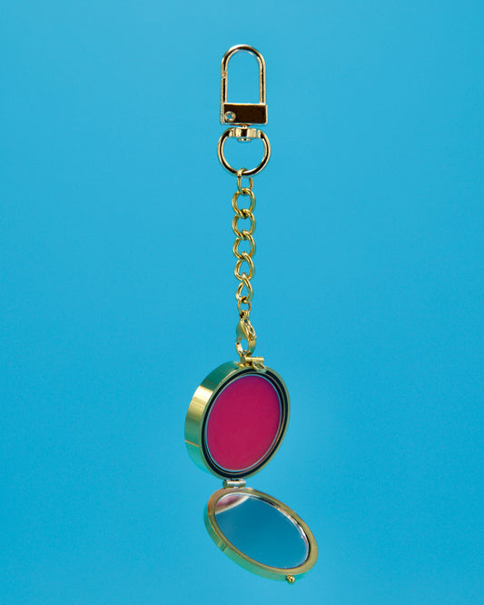 a gold circle locket on a 3 cm gold chain with a hot ink lip balm inside Featured on a blue background 