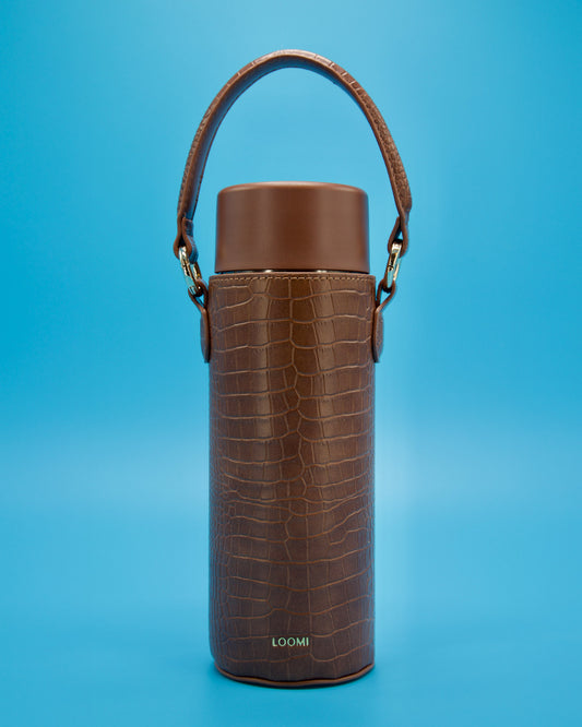 “Espresso Loomi bottle styled in a brown croc Slip with a coordinating brown lid, photographed on a reflective blue surface.”
